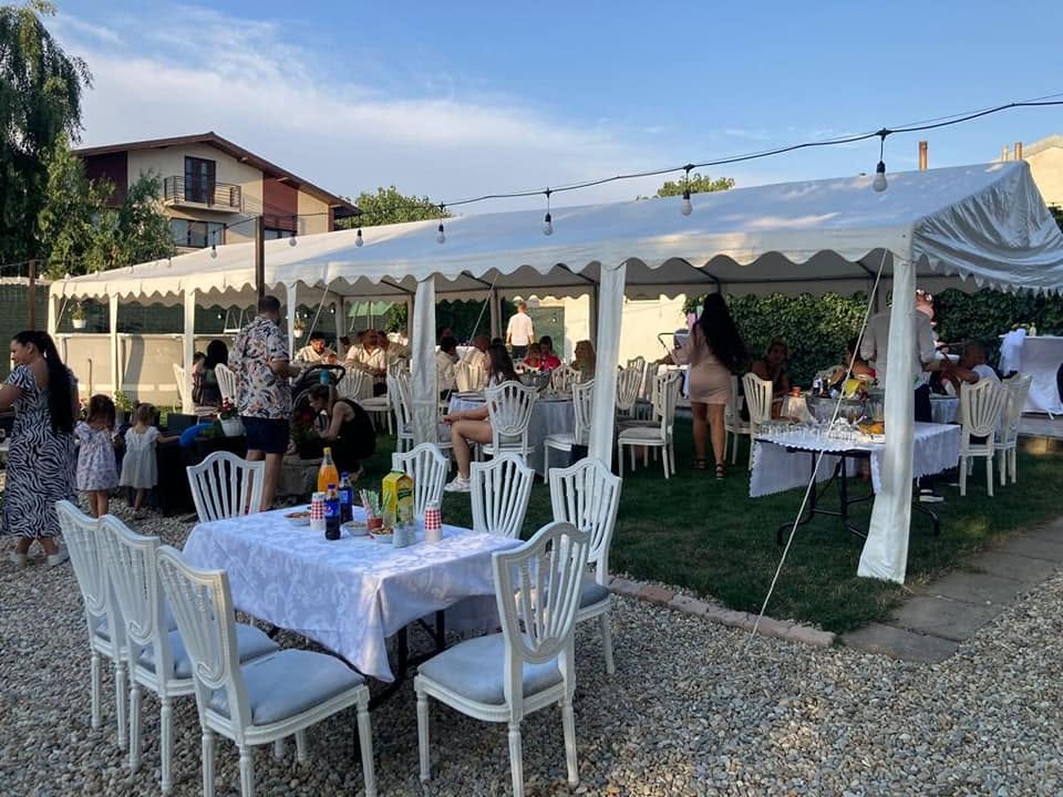Cort alb elegant amenajat în grădină la apus, cu ghirlande luminoase